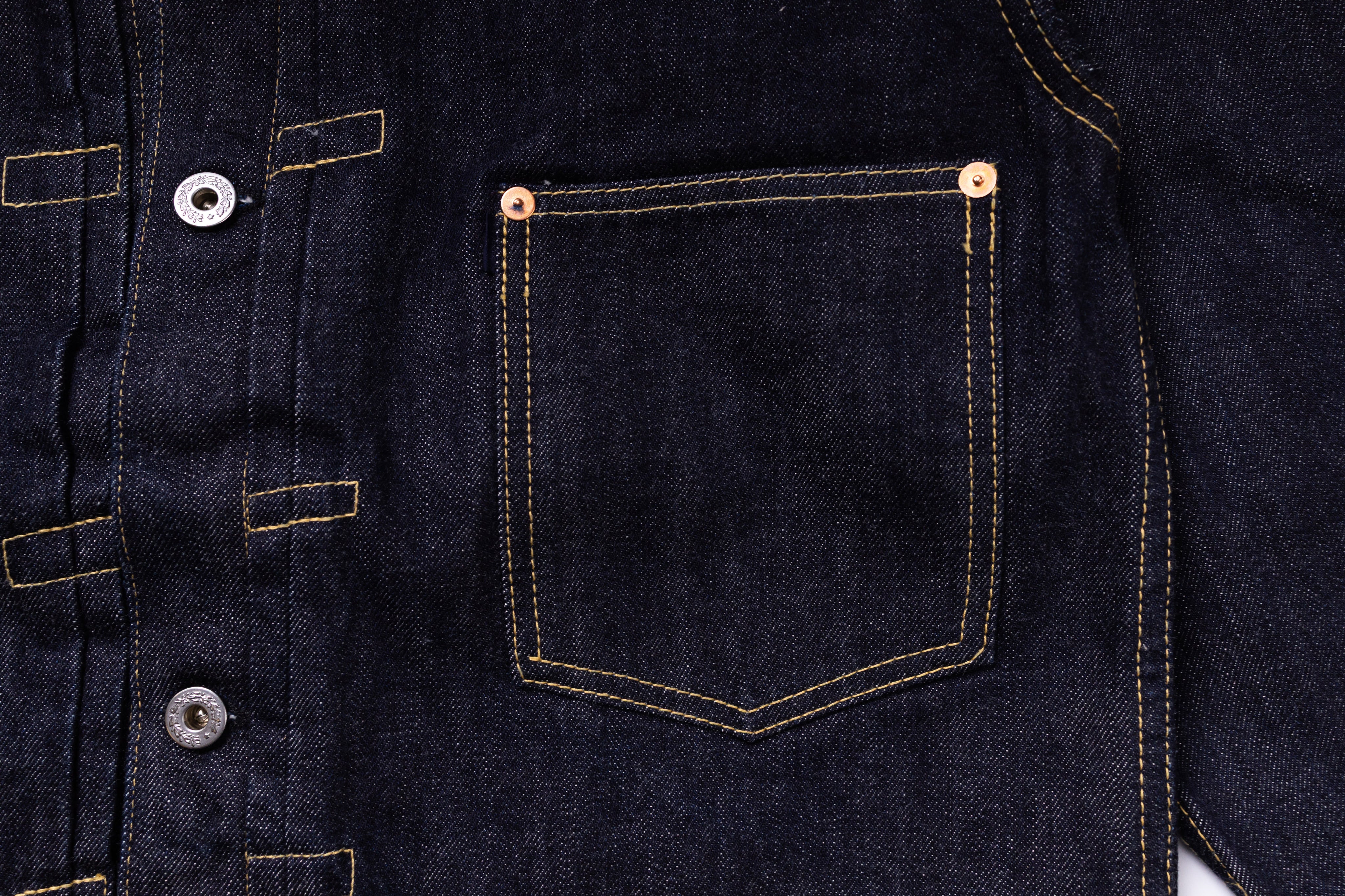 Close-up of a dark blue denim jacket with buttons and a pocket.