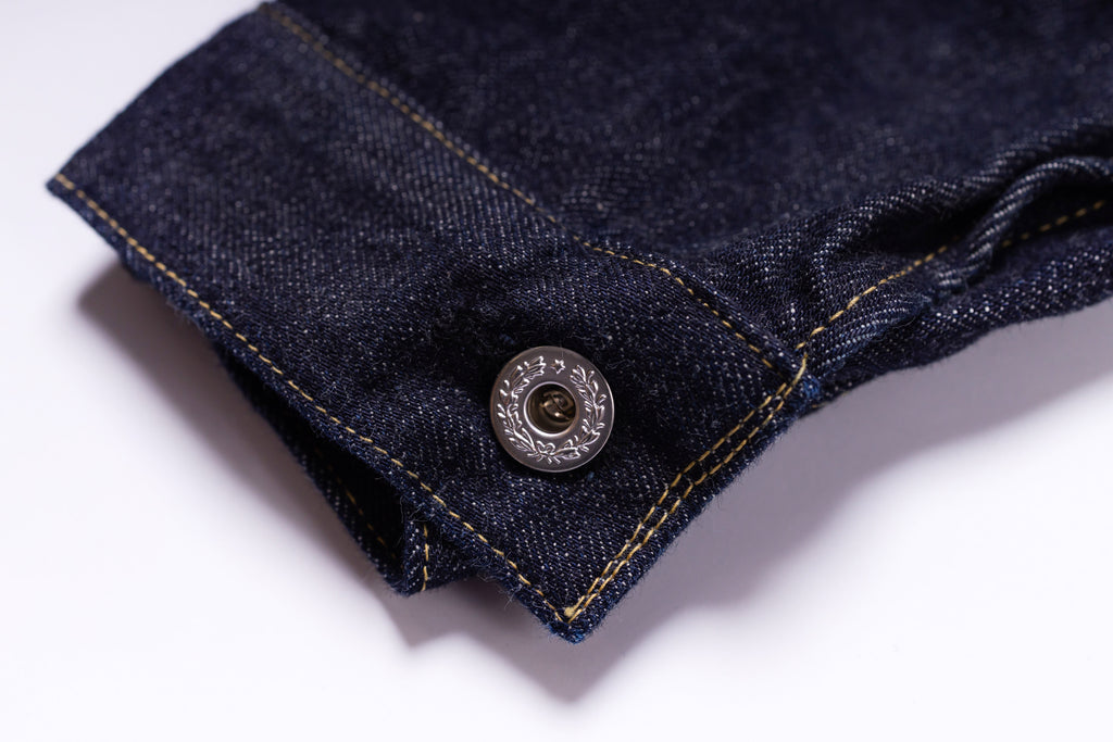 Close-up of a button on a denim fabric with a white background