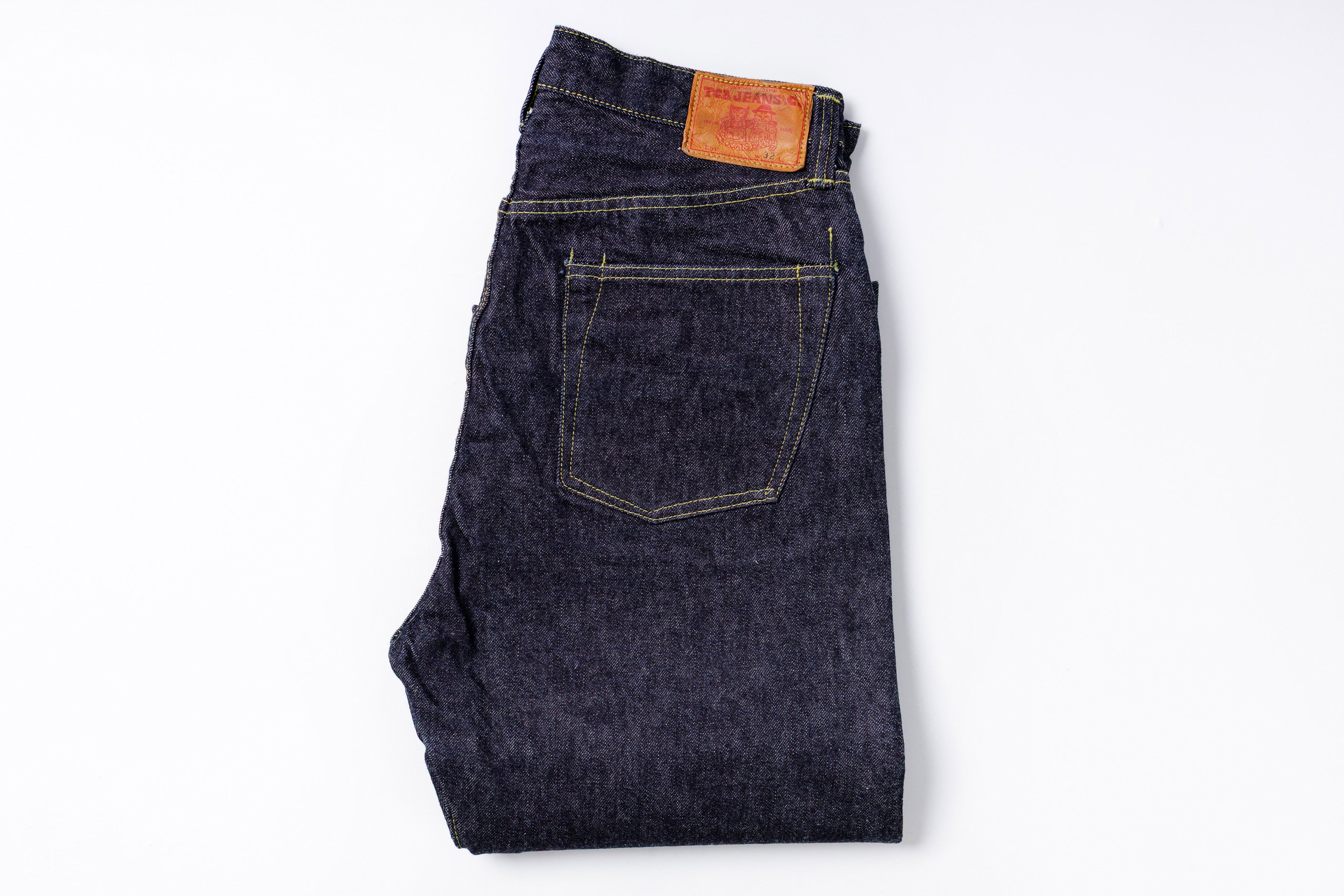 Folded pair of dark blue jeans with a brand label on a white background