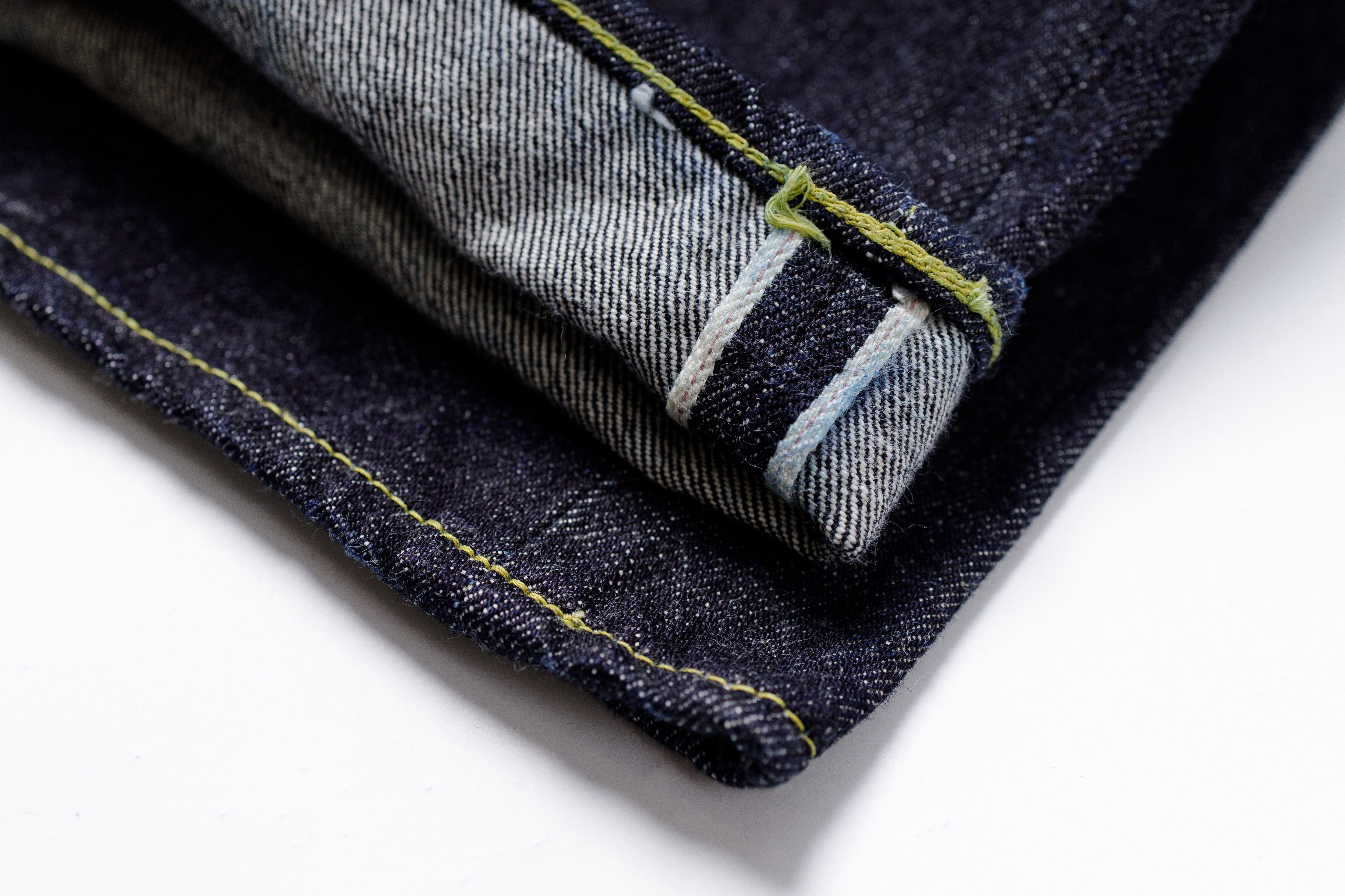 Close-up of folded dark blue denim jeans with visible stitching on a white background