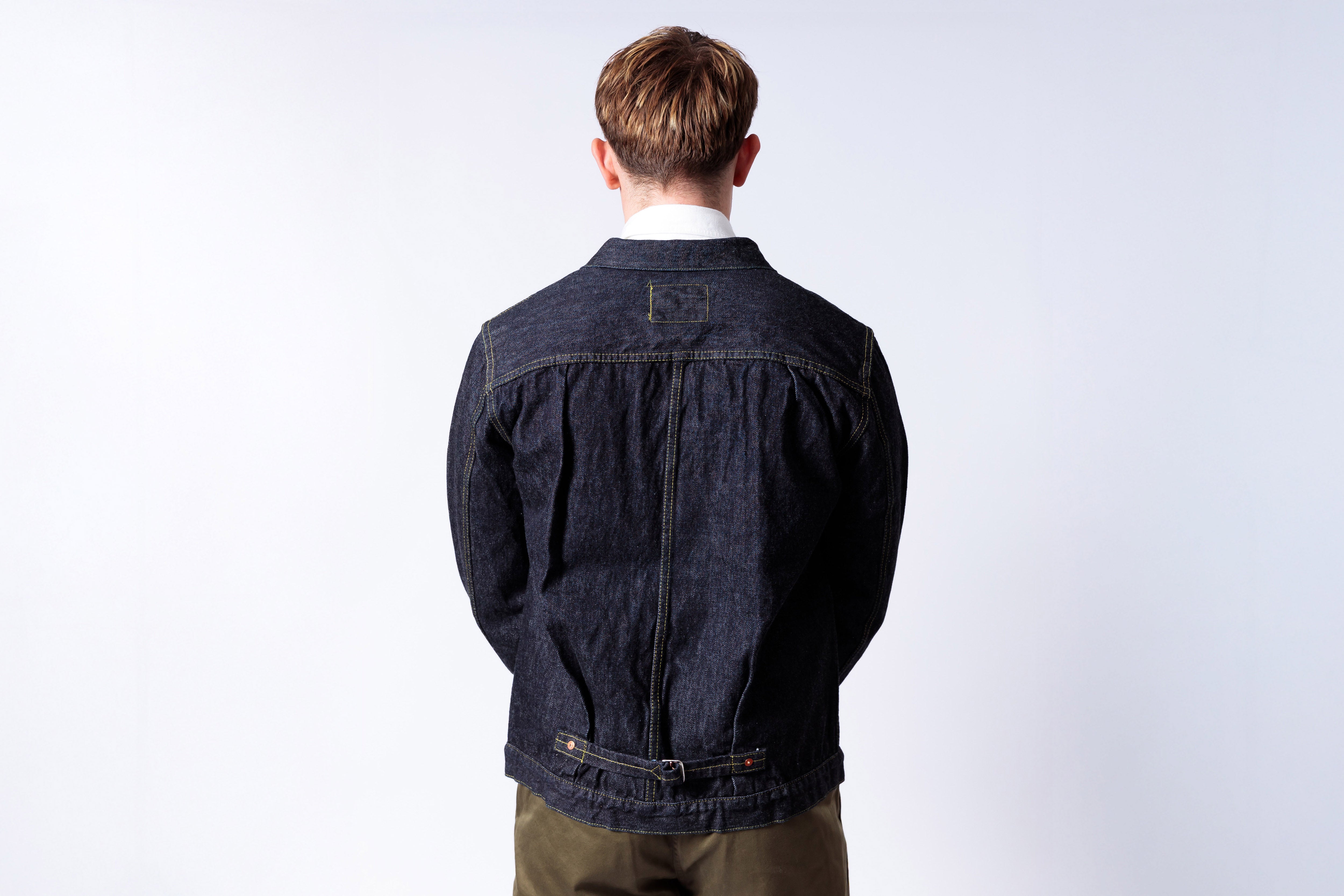 Person wearing a dark denim jacket on a white background