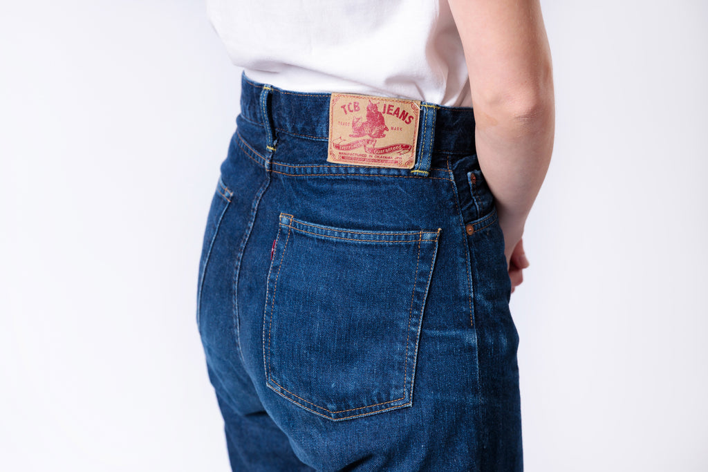 Person wearing blue jeans with a visible Levi's brand label on a white background