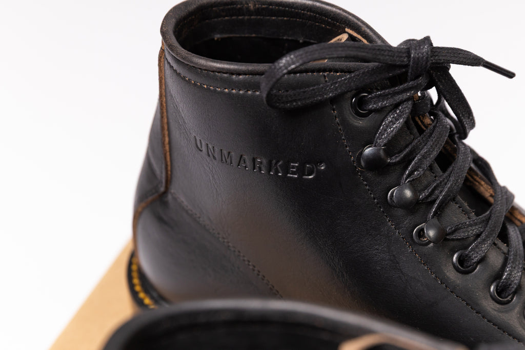 Black leather boot with 'UNMARKED' branding on a white background