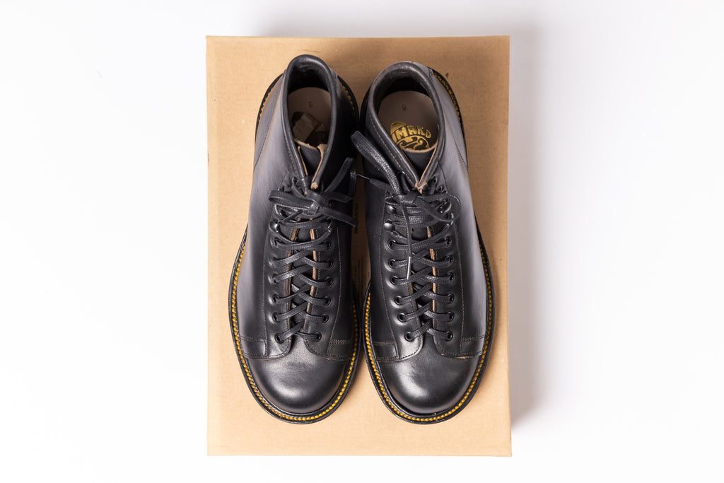 Pair of black leather shoes on a cardboard box with a white background