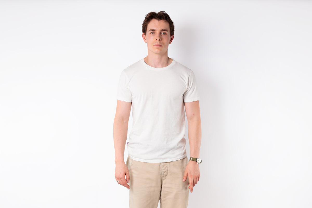 Man wearing a white t-shirt and beige pants against a white background