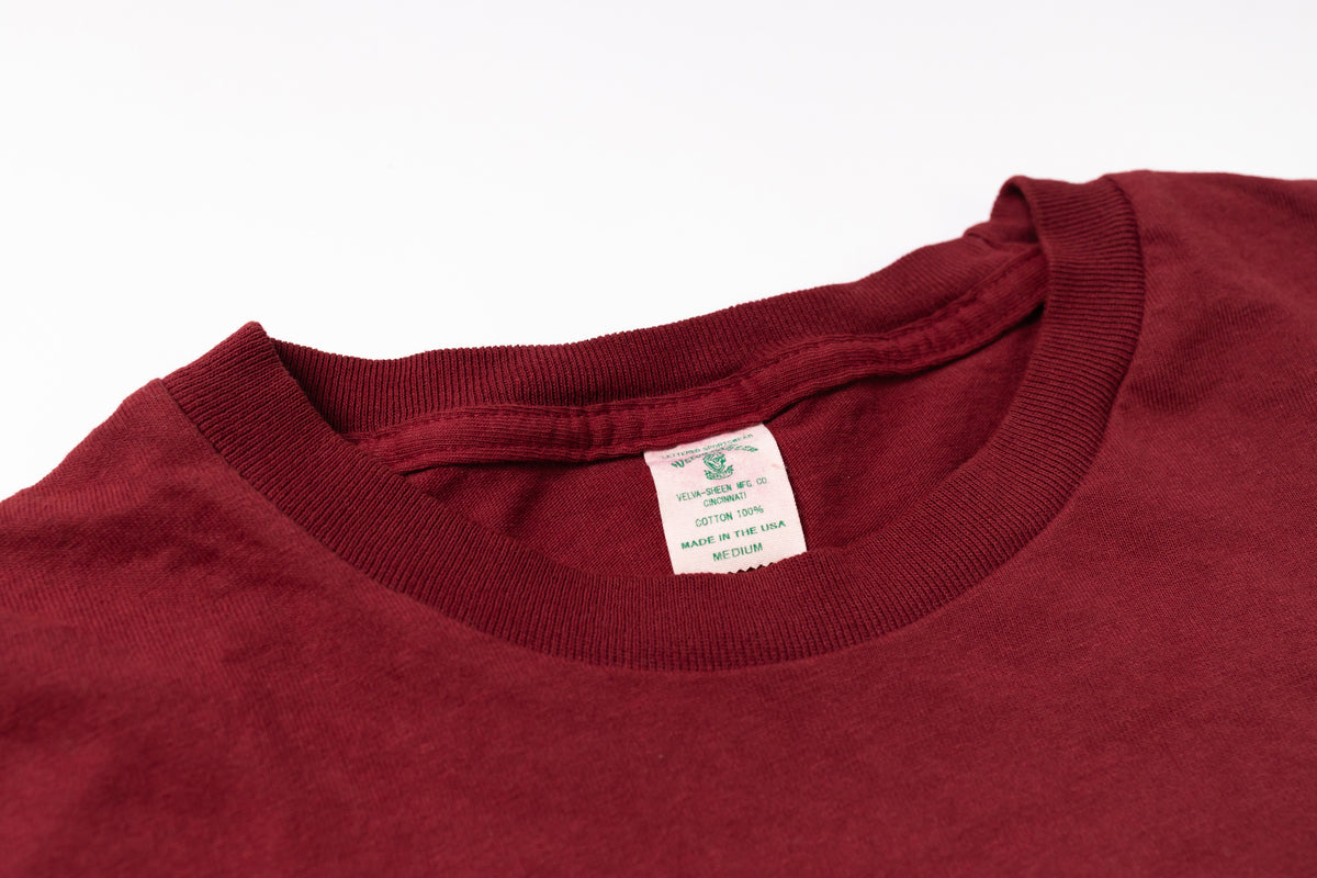 Close-up of a maroon shirt with a tag on a white background