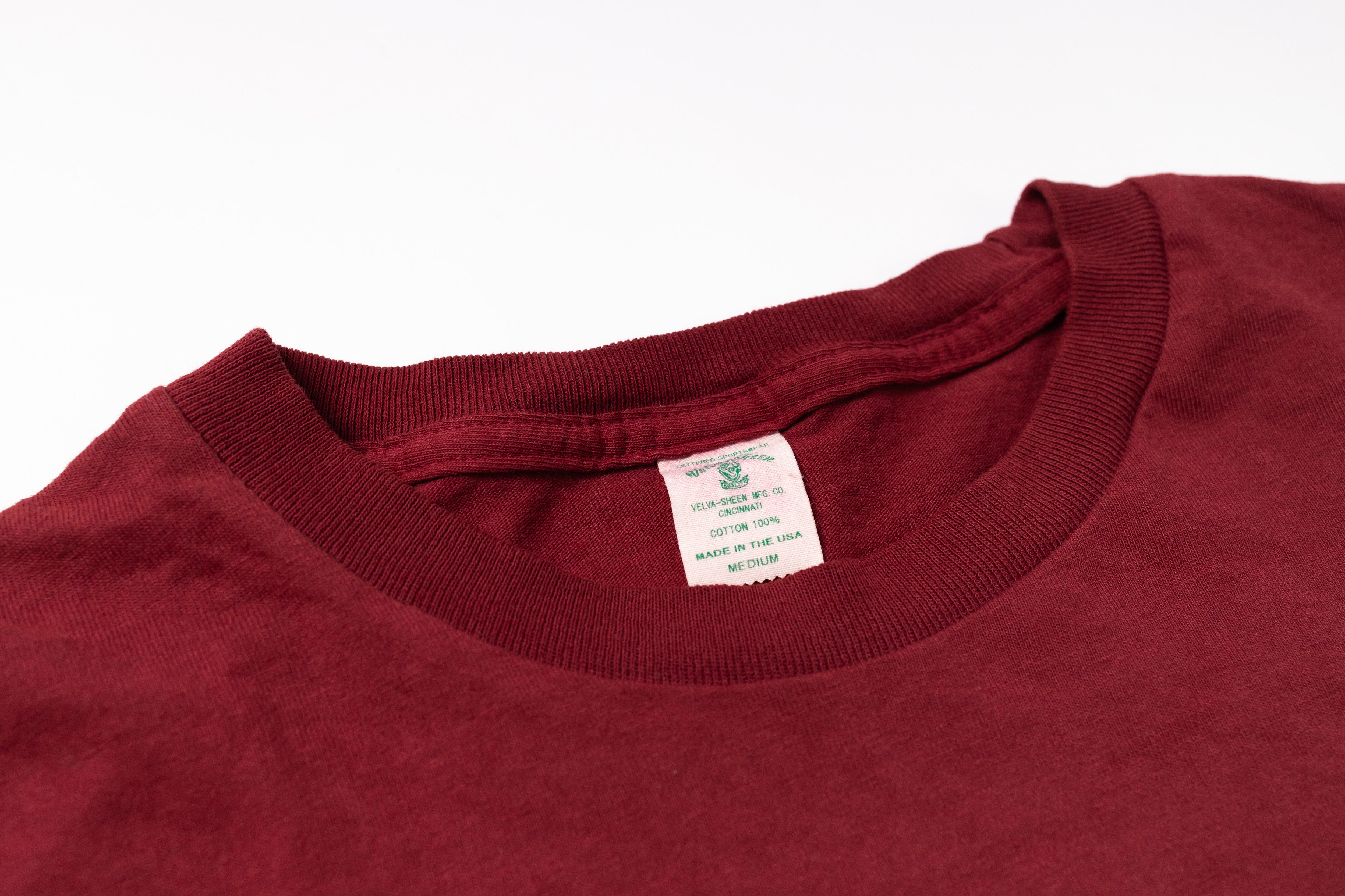 Close-up of a maroon shirt with a tag on a white background
