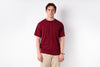 Man wearing a red t-shirt and beige pants against a white background