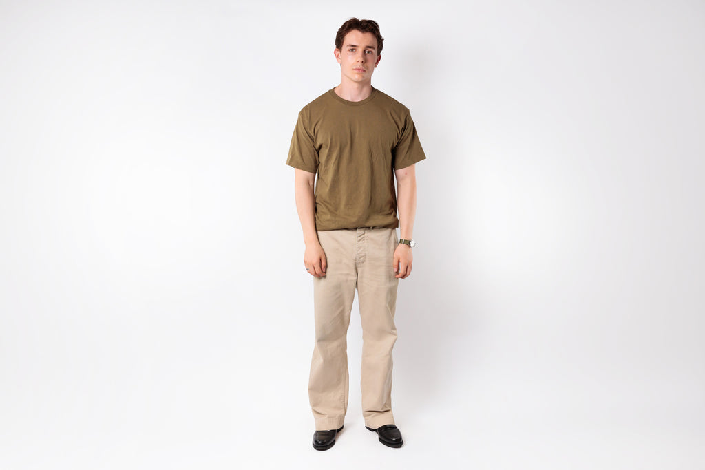 Man wearing a green t-shirt and beige pants on a white background
