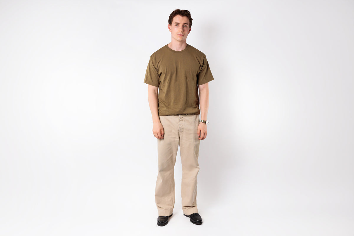 Man wearing a green t-shirt and beige pants on a white background