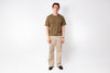 Man wearing a green t-shirt and beige pants on a white background
