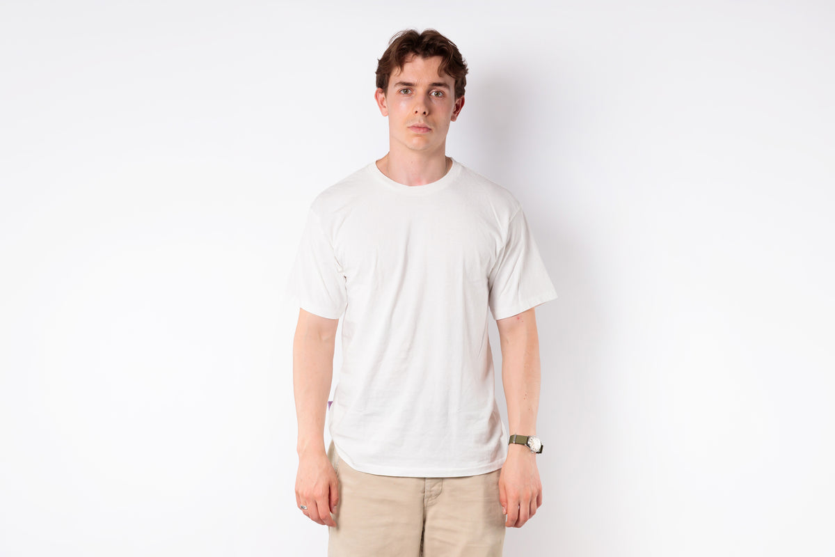 Person wearing a plain white t-shirt and beige pants against a white background