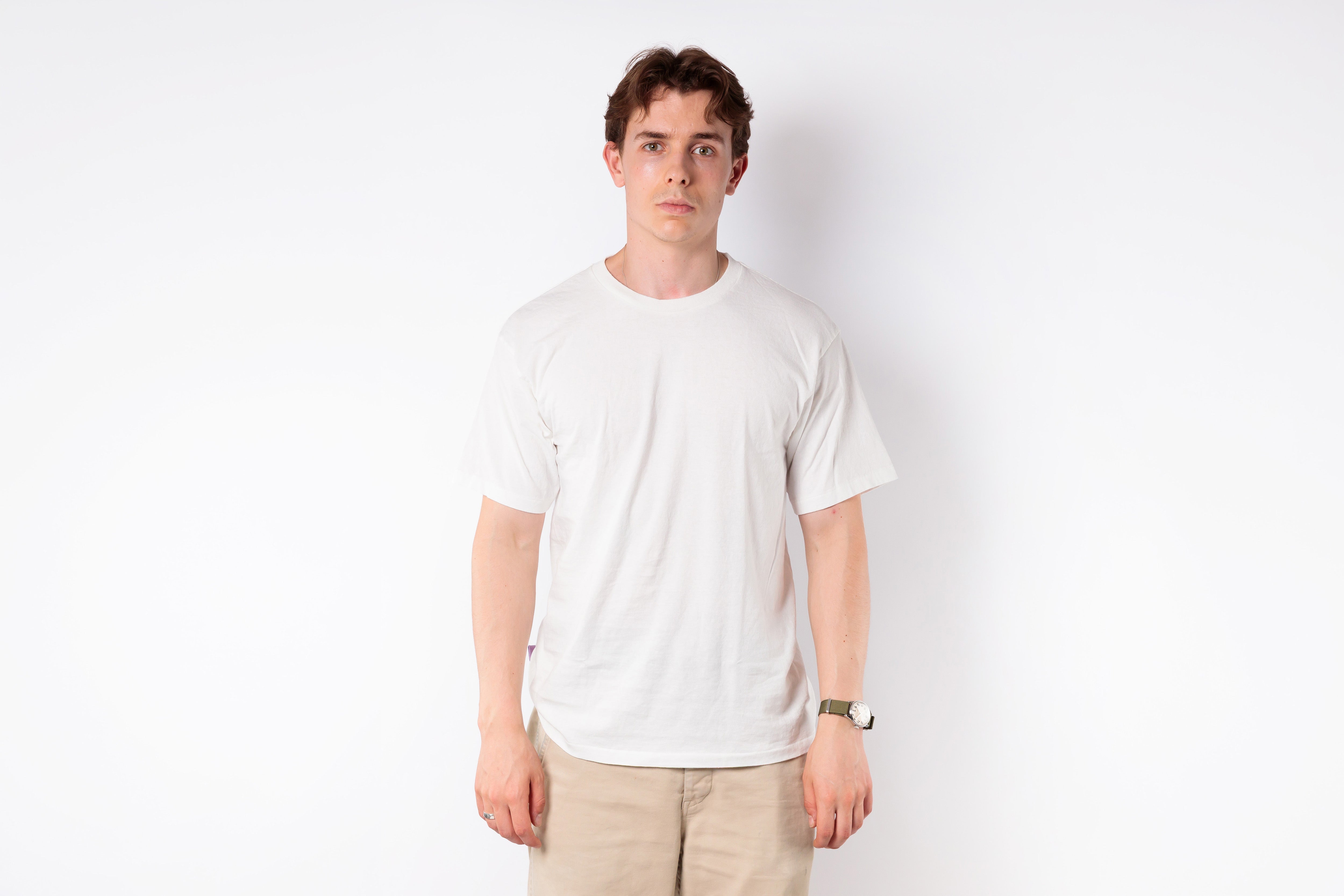 Person wearing a plain white t-shirt and beige pants against a white background