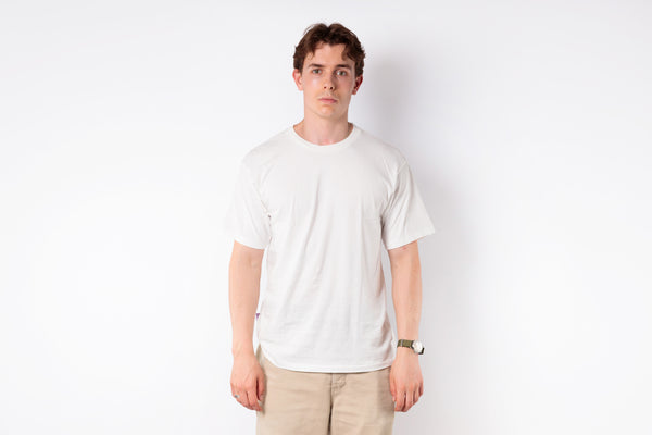 Person wearing a plain white t-shirt and beige pants against a white background