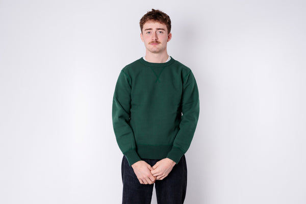 Person wearing a green sweater against a white background