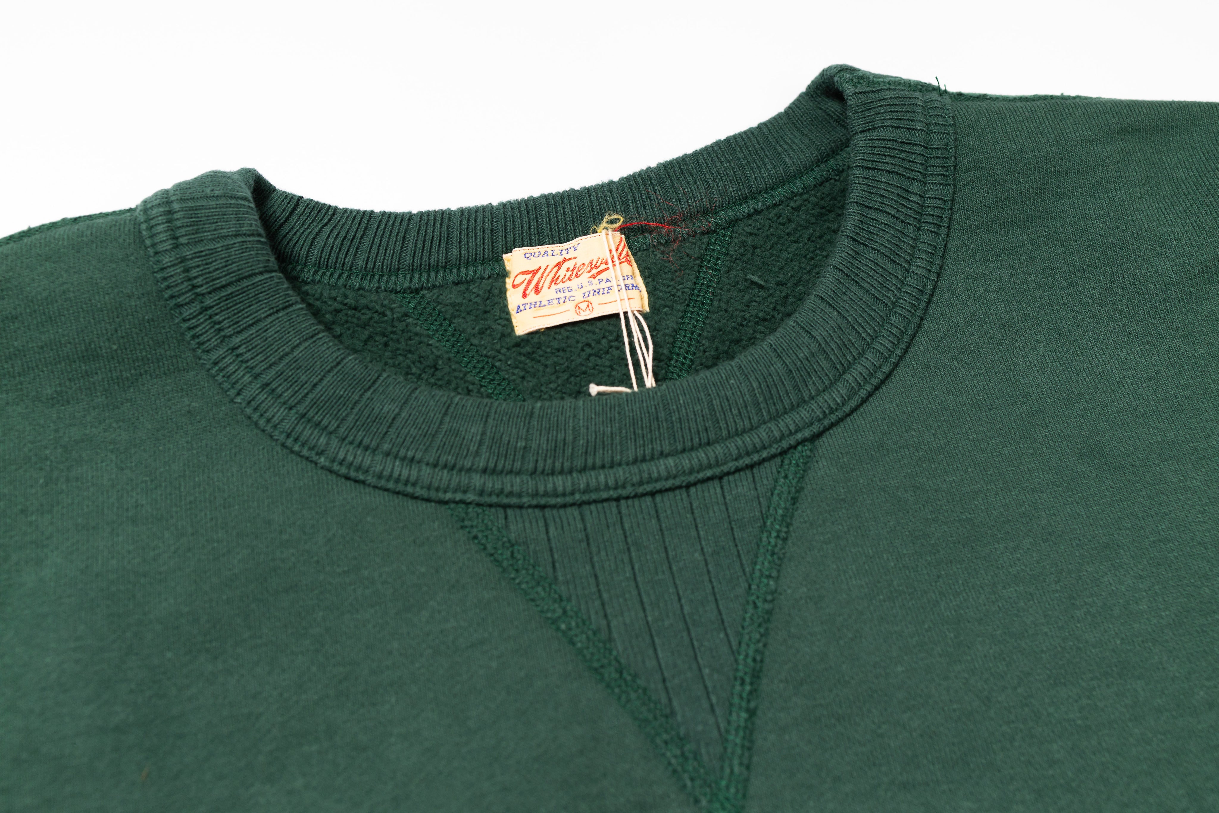 Green sweater with a brand tag on a white background
