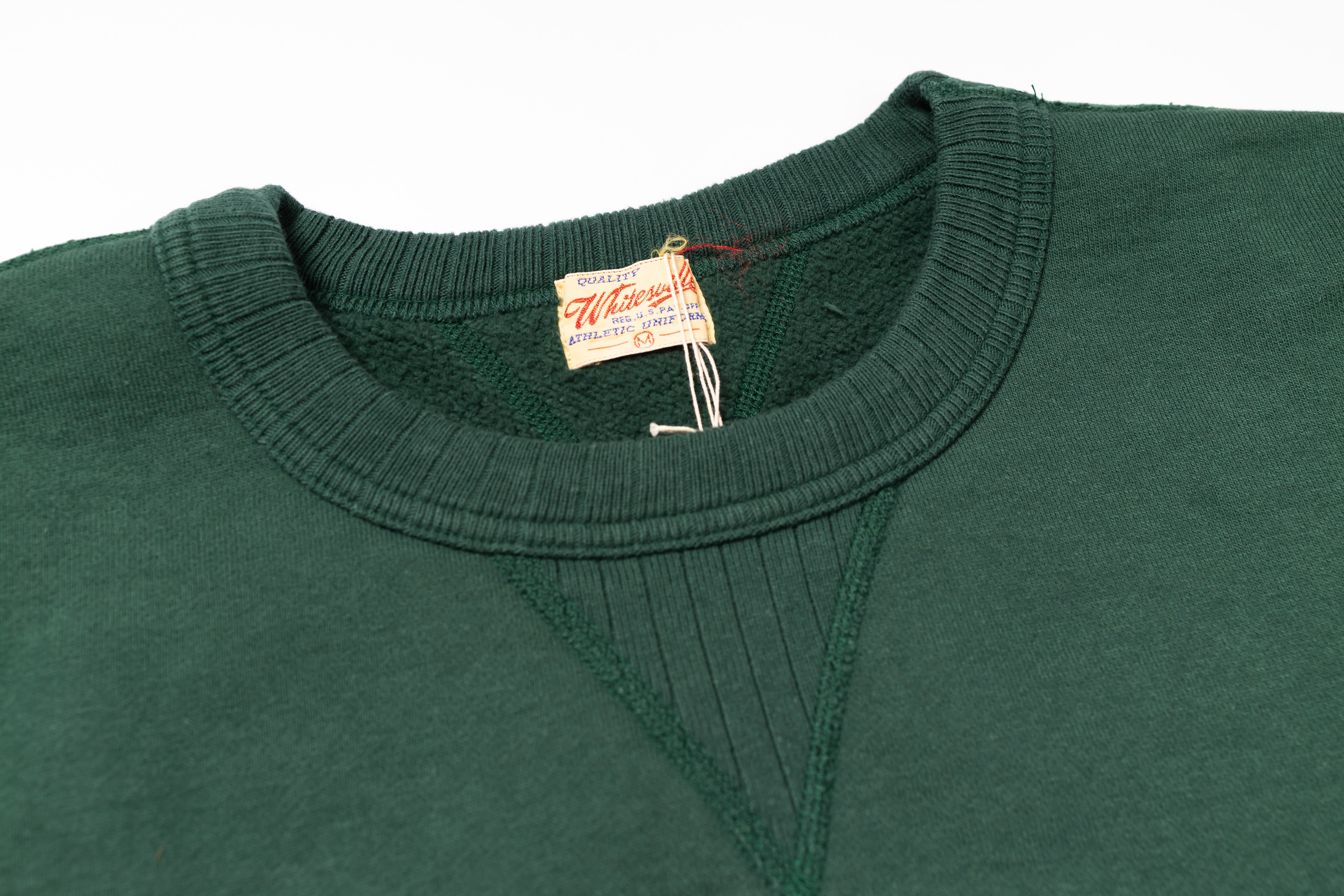 Green sweater with a brand tag on a white background