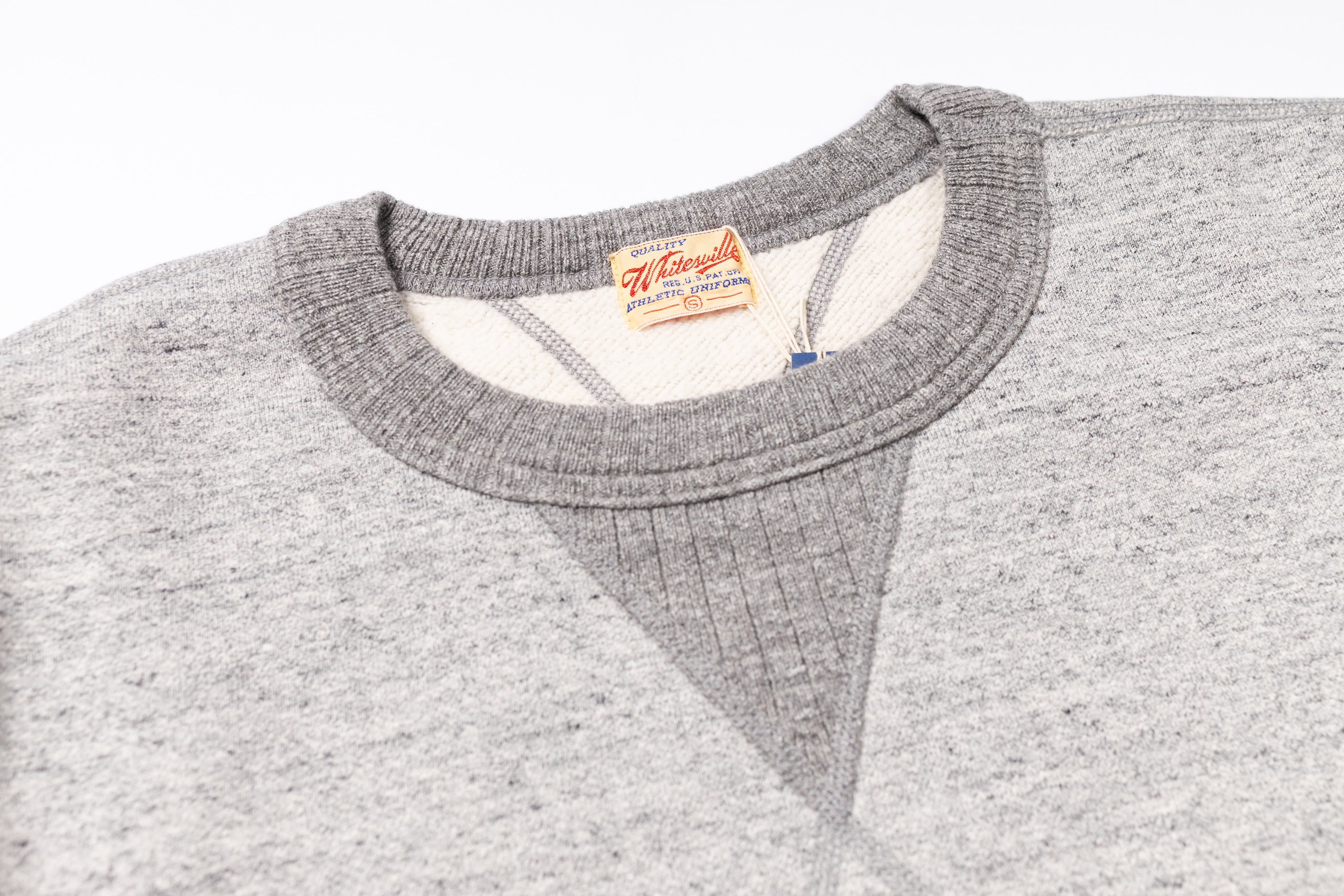 Gray sweater with a brand label on the collar against a white background