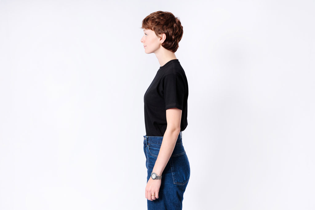Person wearing a black top and blue jeans on a white background