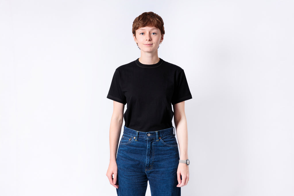 Person wearing a black t-shirt and blue jeans on a white background