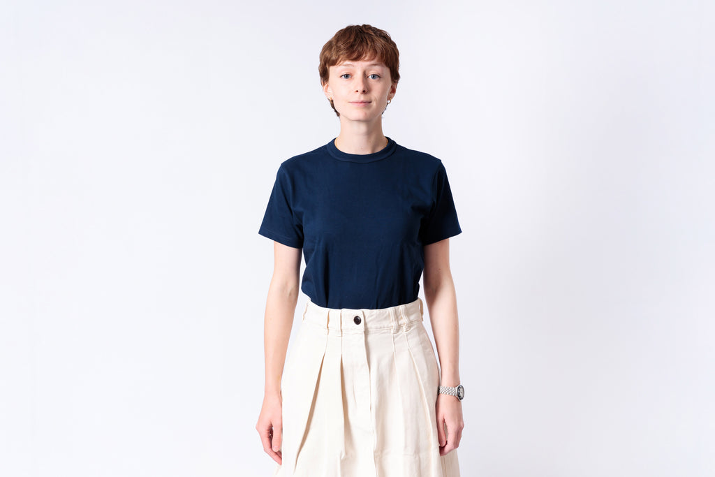 Person wearing a navy blue t-shirt and beige pants on a white background
