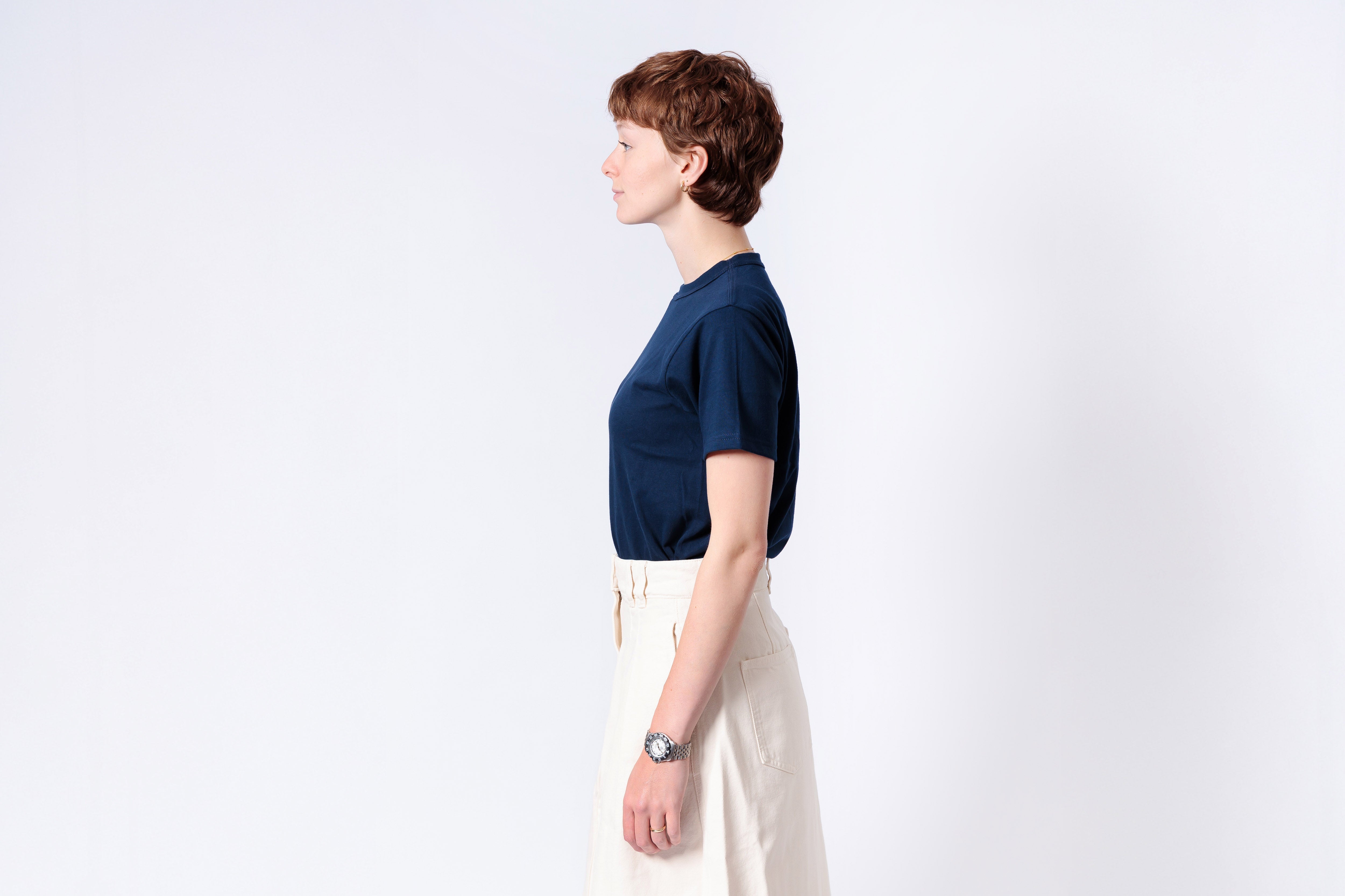Person wearing a navy blue shirt and white pants on a light gray background