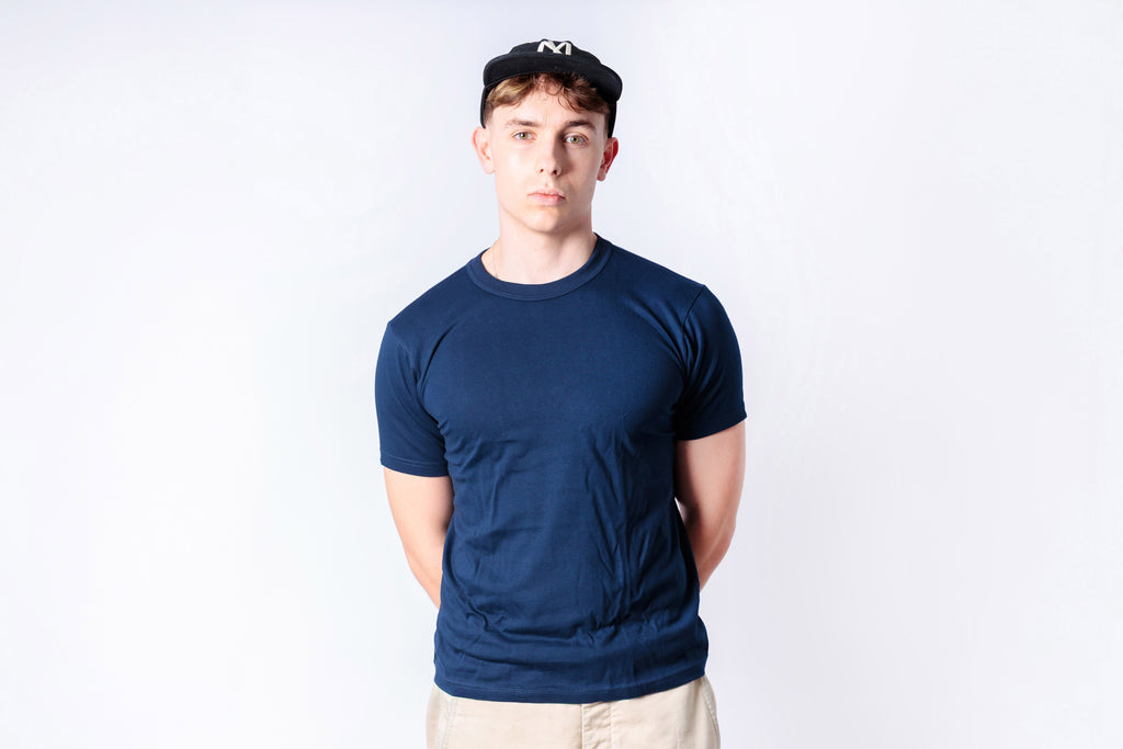 Person wearing a navy blue t-shirt and cap on a white background